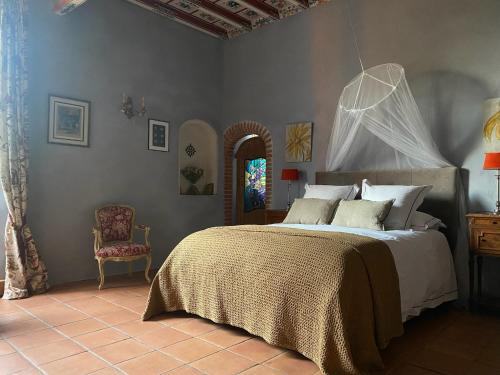 a bedroom with a large bed and a chair at Manoir du Bouyssou in Cintegabelle