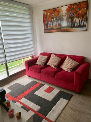 a red couch in a living room with a window at Departamento a pasos Terminal Rodoviario in Temuco
