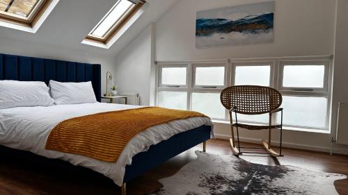 Schlafzimmer mit einem Bett, einem Stuhl und Fenstern in der Unterkunft Aldo's 2 Bedroom Townhouse London N1 in London