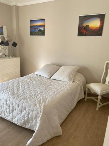 a bedroom with a white bed and a chair at Casa Alves in Palmela