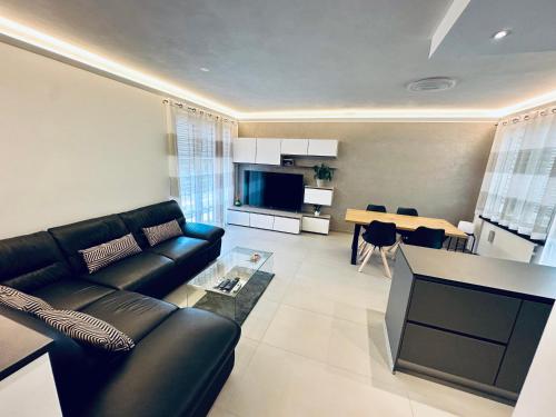 sala de estar con sofá de cuero negro y mesa en Wonderful Apartament, Near The Lake en Lugano