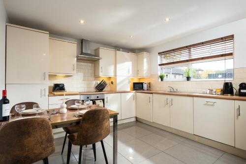 a kitchen with white cabinets and a wooden table at Cosy Modern City Centre 2 Bed Apartment in Belfast