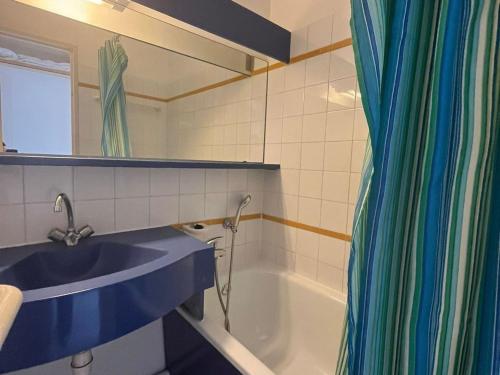 La salle de bains est pourvue d'un lavabo et d'une baignoire avec rideau de douche. dans l'établissement Confort 2 pièces avec terrasse, piscine et parking - FR-1-504-673, à Saint-Raphaël