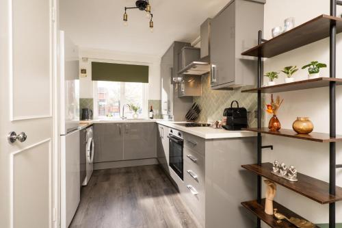 eine Küche mit weißen Schränken und Holzböden in der Unterkunft City Vibe Haven - Modern 2 Bed Apartment with High Speed WI-FI in Belfast