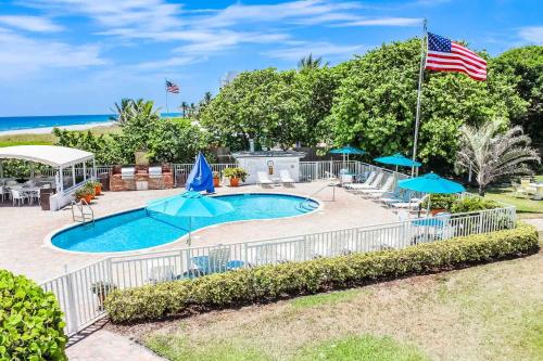 uma piscina com uma bandeira americana e o oceano em Berkshire on the Ocean (timeshare resort) em Delray Beach