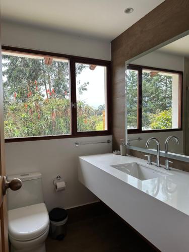 a bathroom with a sink and a toilet and a mirror at El Tambo Retreat in Machachi