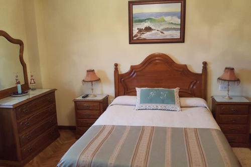 a bedroom with a bed with two dressers and two lamps at Chalet en Miño con vistas al mar in Miño