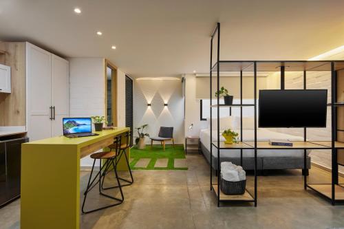 a living room with a yellow desk and a television at Altio Hotel in Cali