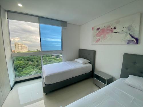 1 dormitorio con 2 camas y ventana grande en Apartamentos Ocean Club - Cerca al Mar by SOHO, en Santa Marta