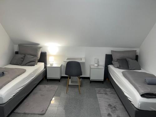 two beds in a room with a chair and a desk at Apartment by Harbali in Schüttorf