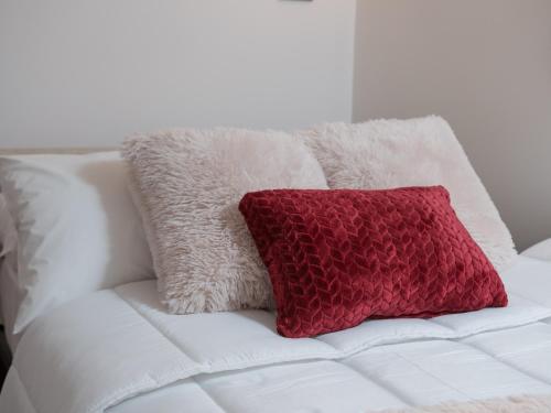 a red pillow on a white couch with white pillows at Comfy and Cosy Studio Kalamata in Kalamata