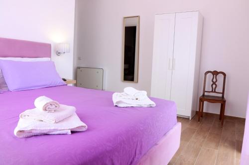 Un dormitorio con una cama morada con toallas. en Antares Rooms en Castellabate
