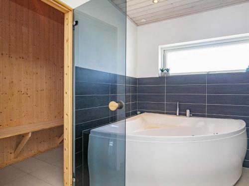 La salle de bains est pourvue d'une baignoire et d'une fenêtre. dans l'établissement 10 person holiday home in L kken, à Løkken
