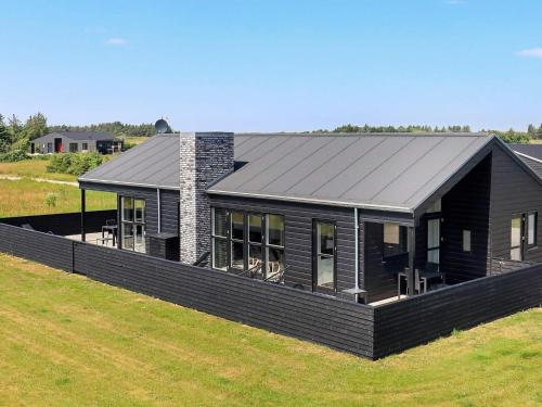 une maison avec un toit noir sur un champ dans l'établissement 10 person holiday home in L kken, à Løkken