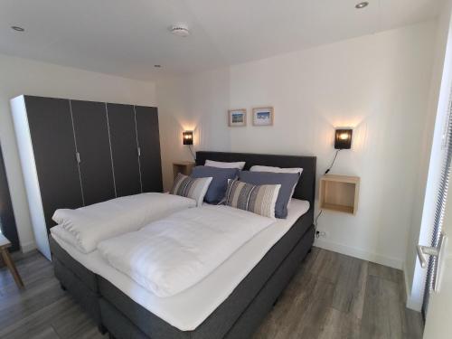 a bedroom with a large bed with white sheets and blue pillows at Vakantiewoningen Eyveld in Beesel