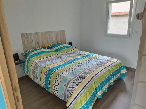 Una cama con un edredón colorido en un dormitorio en Gîte, en Les Moitiers-dʼAllonne