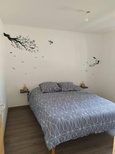 1 dormitorio con 1 cama con edredón azul y flores en la pared en Gîte, en Les Moitiers-dʼAllonne