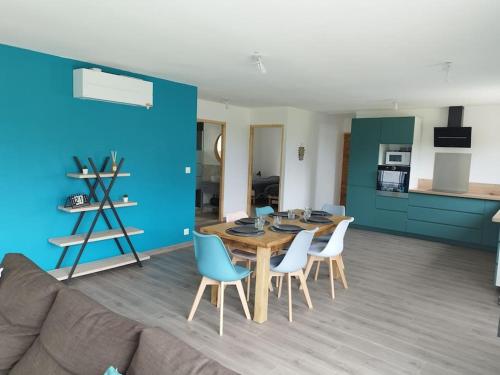 sala de estar con mesa, sillas y pared azul en Gîte, en Les Moitiers-dʼAllonne