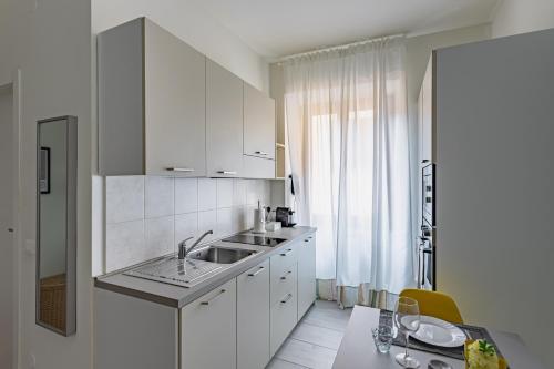une cuisine blanche avec un évier et une table dans l'établissement Casa Elena - vicino al Castello - by Host4U, à Pavia