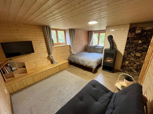 Zimmer mit Sofa und Kamin in einer Hütte in der Unterkunft Chata 1-Padesátka in Bedřichov
