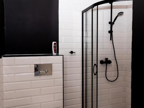 a bathroom with a shower with a black and white at Brama do lasu - Domek Relaksu in Borków