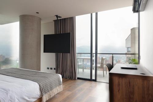 a bedroom with a bed and a desk and a large window at Kiin Living- "Child-free coliving" in Medellín