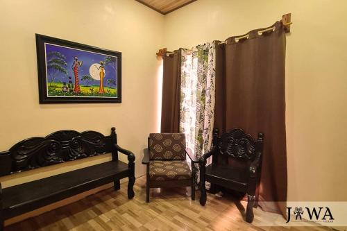 a bedroom with two beds and a chair and a picture at Villas Jawa in Puerto Limón