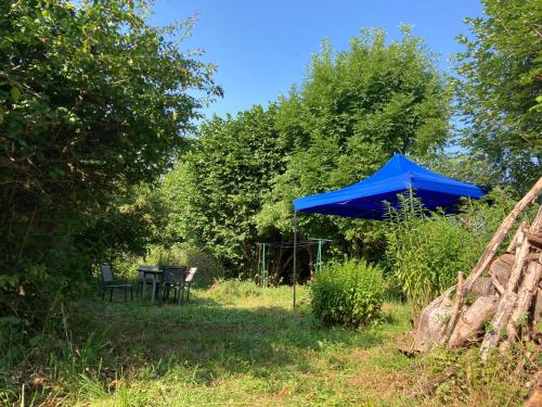 un paraguas azul y una mesa y sillas en un patio en Studio à la campagne proche du lac, 