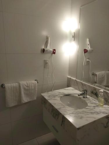 La salle de bains blanche est pourvue d'un lavabo et d'un miroir. dans l'établissement Departamento nuevo en Puerto Madero - Torre 11 de Madero Harbour -, à Buenos Aires