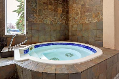 a jacuzzi tub in a bathroom with a window at Best Western PLUS City Centre Inn in Edmonton