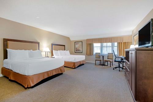 a hotel room with two beds and a flat screen tv at Best Western Plus Emerald Isle Hotel in Sidney