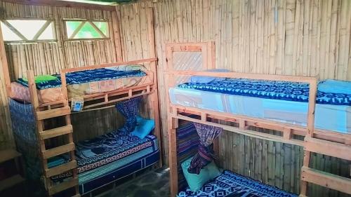 a room with three bunk beds in a wooden cabin at The Hub - Centro Sakbe in San Juan La Laguna