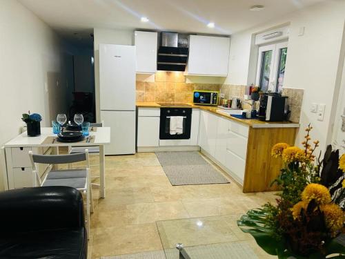 a kitchen with white cabinets and a table and a counter at Petite Maison Proche aéroport Charles de Gaulles in Drancy