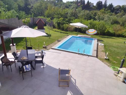 a pool with a table and chairs and an umbrella at Dunavski konaci in Brestovik