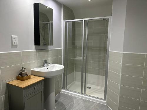 uma casa de banho com uma cabina de duche em vidro e um lavatório. em 4 bed, 2 bath, Sky TV, Gym, Parking and Garden em Hitchin