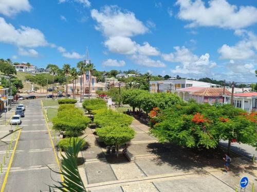 una calle de la ciudad con árboles y edificios en un día soleado en Le Tamarinier en Sainte-Anne