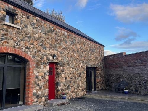un edificio de ladrillo con una puerta roja en el lateral en The Stone Barn, en Magheralin