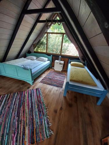 an attic bedroom with two beds and a rug at Magaze de Luxe in Gradačac