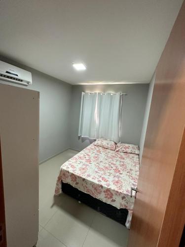 - une petite chambre dotée d'un lit avec un couvre-lit floral dans l'établissement Apê do Tigas - Praia dos Milionários, à Ilhéus