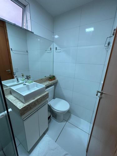 a white bathroom with a toilet and a sink at Apê do Tigas - Praia dos Milionários in Ilhéus