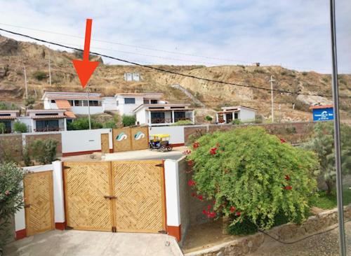 ein Haus mit Holztüren und einem Busch in der Unterkunft Casuarinas Del Mar Chalet de 2 habitaciones in Canoas De Punta Sal