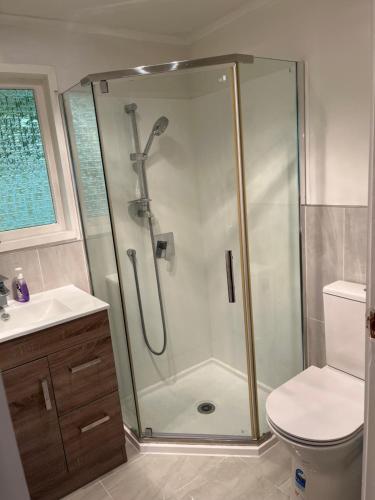 a bathroom with a shower with a toilet and a sink at Hillcrest Homestay, NorthShore, Auckland in Auckland