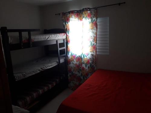 a bedroom with a bunk bed and a window with a curtain at casa na praia Itanhaém in Guarulhos