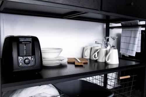 un mostrador negro con tostadora y platos. en Rustic Rails Accommodation, en Dargaville