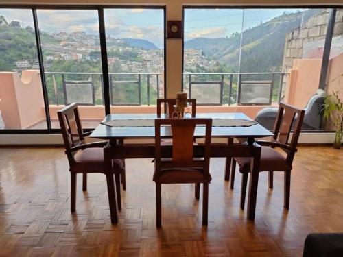 a table and chairs in a room with a large window at Hermoso departamento en Quito con servicios incluidos in Quito