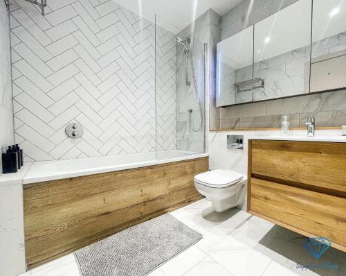 a bathroom with a tub and a toilet and a sink at M1 City Centre Luxe 3 Bed 3 Bath Apartment in Manchester