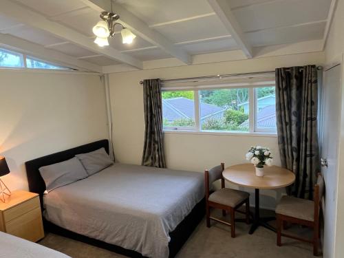 a bedroom with a bed and a table and a window at Hillcrest Homestay, NorthShore, Auckland in Auckland