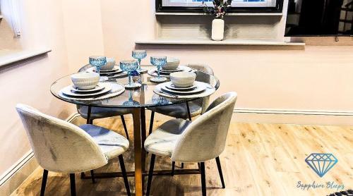 a dining room table with chairs and a glass table with cups at M1 City Centre Luxe 3 Bed 3 Bath Apartment in Manchester