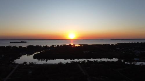 a sunset over a body of water with the sun setting at Carmelo RIVERSIDE Bungalows in Carmelo