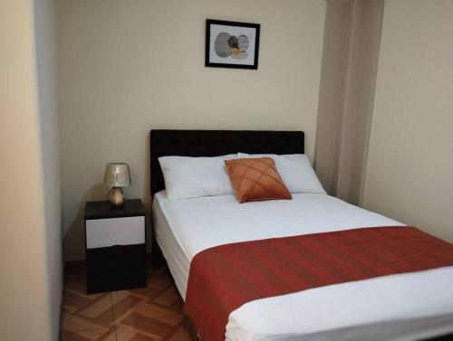 um quarto com uma cama com um cobertor vermelho e branco em Apart Florencia, piscina en el verano! incluye parking y vigilancia 24 horas! em Tacna